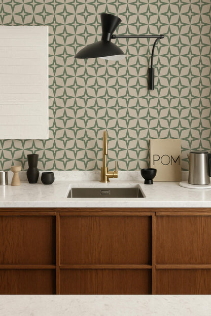 a modern kitchen with a white countertop, wooden cabinets, and a gold faucet above the sink. The walls are adorned with a geometric pattern wallpaper, and a black pendant light hangs above the sink. The kitchen also includes various decorative elements such as a bowl, a vase, and a book.