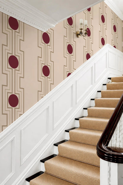 a staircase with a white railing and a beige carpeted step. The walls behind the stairs have a patterned wallpaper with red circles and lines.