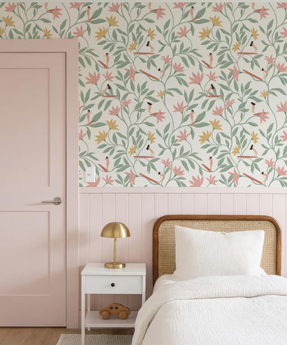 a bedroom with a pink door, a white bed with a wooden headboard, and a white nightstand with a lamp. The wall behind the bed has a floral wallpaper pattern in shades of pink, green, and yellow.