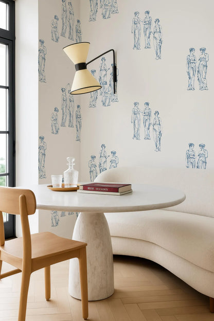 a modern and stylish dining area with a white table, a wooden chair, and a white sofa. The walls are decorated with a repeating pattern of blue and white human figures, creating a visually striking and contemporary atmosphere.
