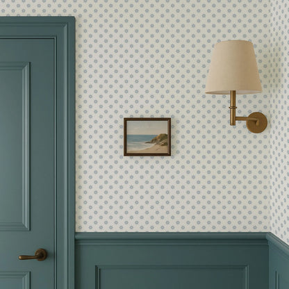 a wallpapered wall with a framed picture hanging on it, a green door, and a wall-mounted lamp.
