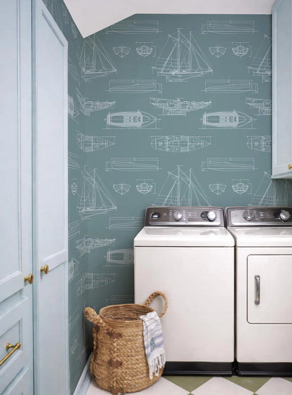 a laundry room with a blue and white color scheme, and a patterned wallpaper with illustrations of boats and ships. The room includes a washer and dryer, a basket, and a towel.