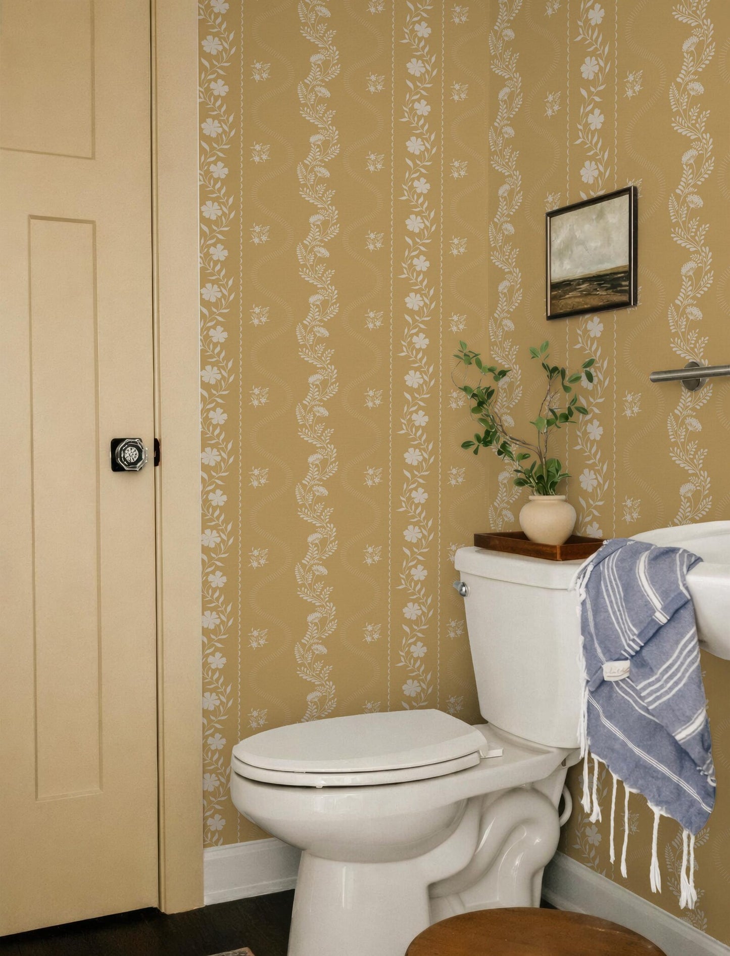 a bathroom with a white toilet, a towel hanging on the side, and a framed picture on the wall.