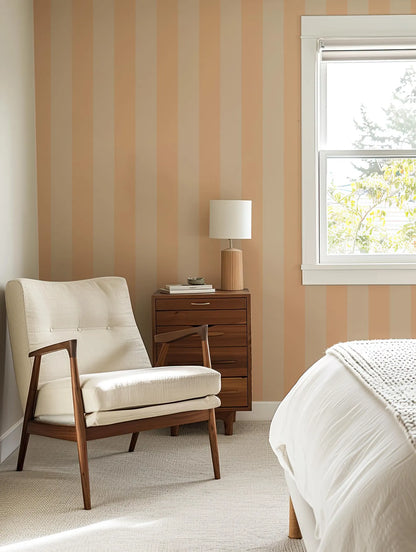 a cozy bedroom with a white armchair, a wooden side table with a lamp, and a window overlooking a tree outside.