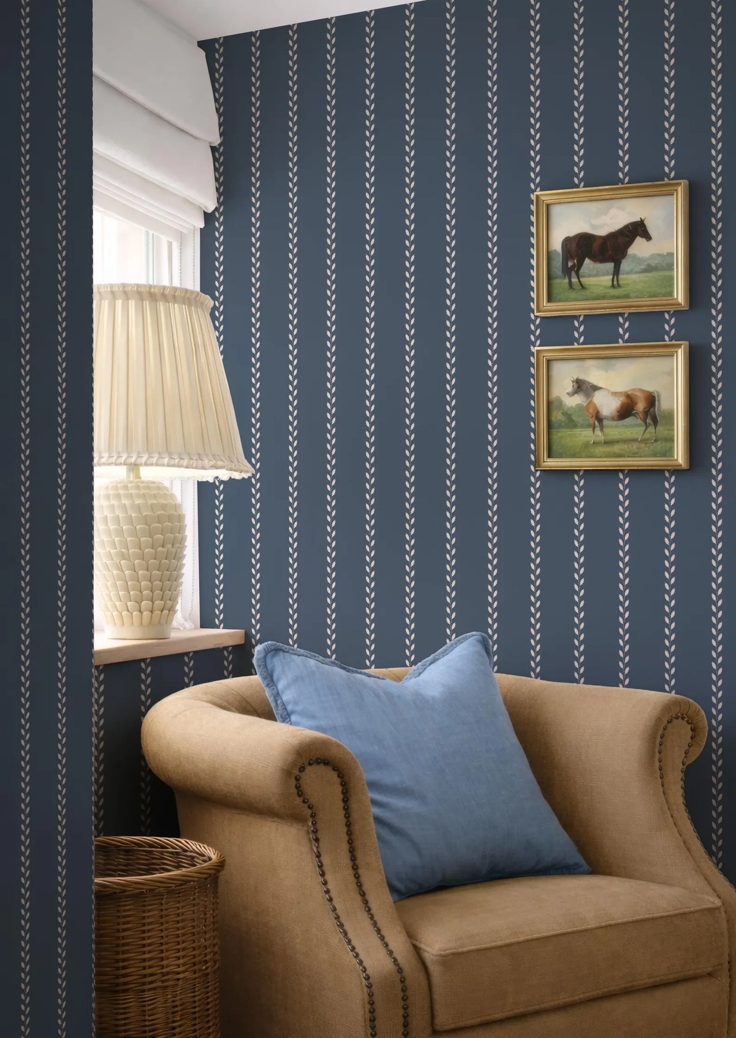 a cozy living room with a beige armchair, a white lamp, and two framed pictures of horses on the wall.