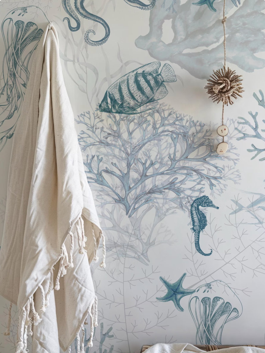 a wallpapered wall with a variety of marine life and ocean-themed illustrations, including a towel, a seahorse, a starfish, and a jellyfish.