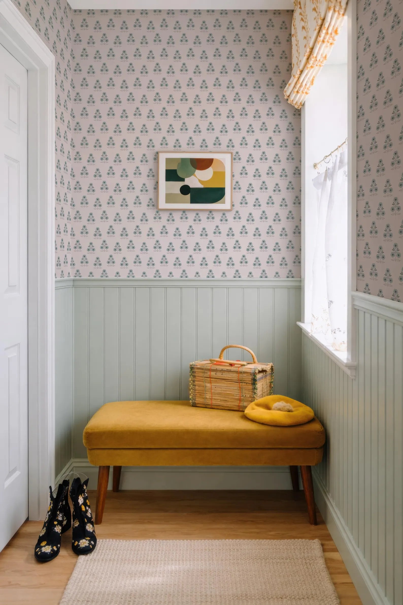 a cozy corner with a yellow bench, a woven basket, and a pair of black and white boots. The walls are adorned with a patterned wallpaper, and a window with a yellow curtain is present. The overall scene conveys a sense of comfort and warmth.