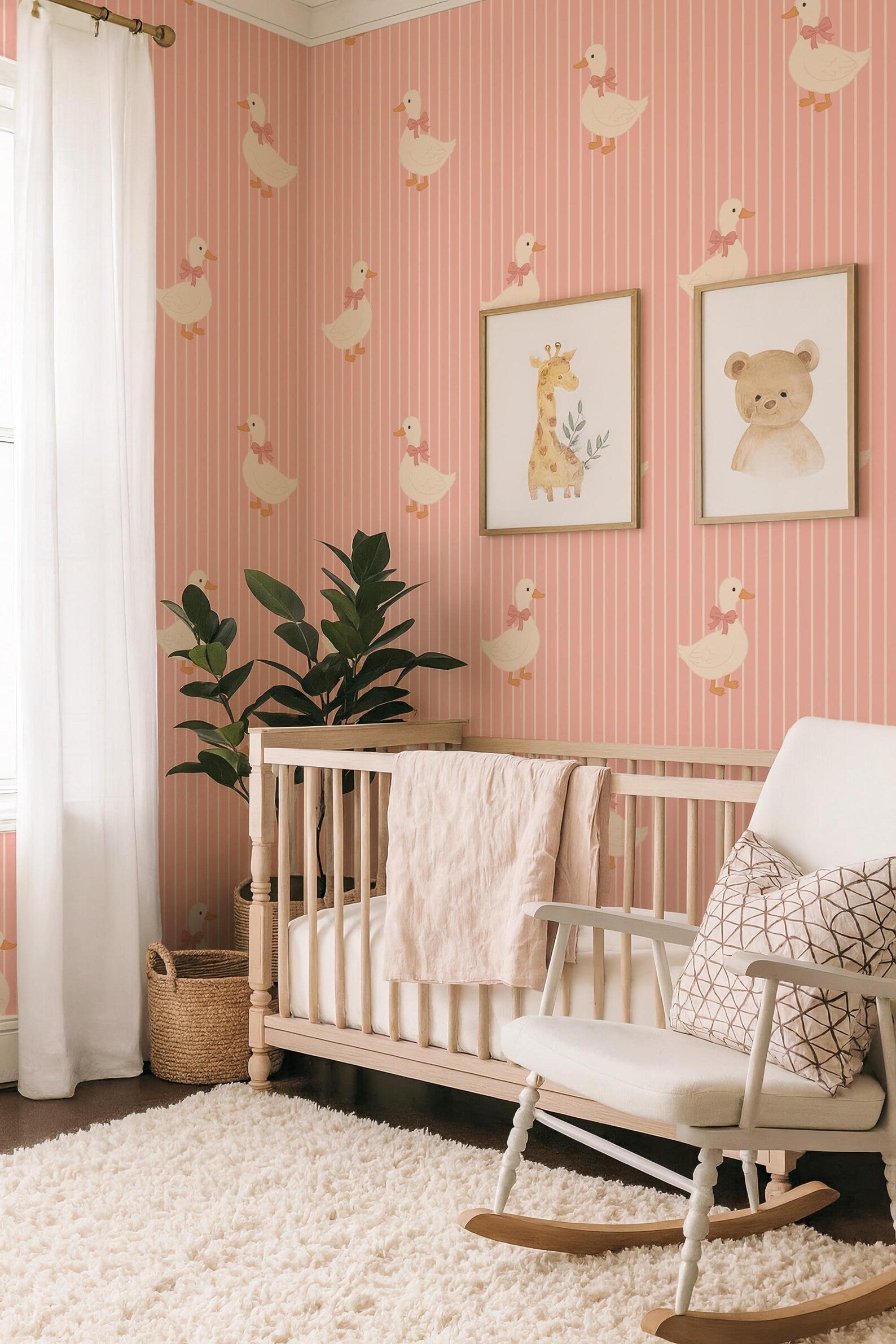 a cozy nursery with a pink and white striped wallpaper, a wooden crib, a white rocking chair, and two framed animal illustrations on the wall.