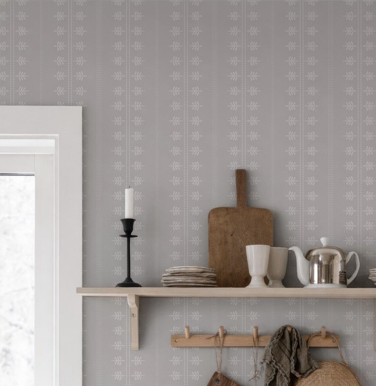 a shelf with various kitchen items, including a wooden cutting board, a white teapot, a white mug, and a stack of plates. The shelf is set against a wall with a gray and white patterned wallpaper.