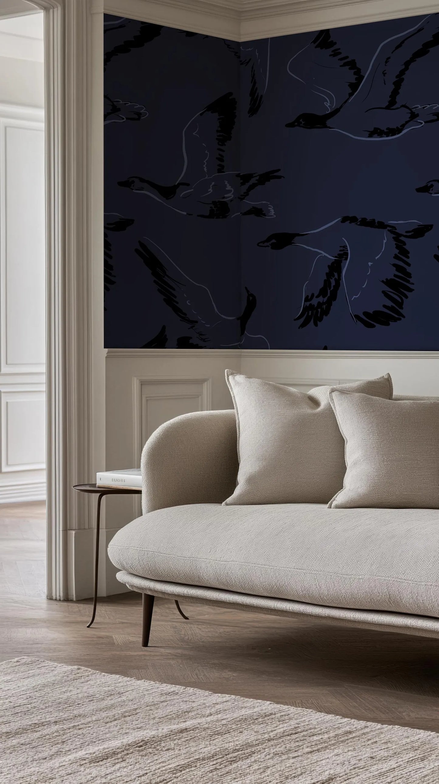 a living room with a white sofa and a dark blue wall with a repeating pattern of black birds.