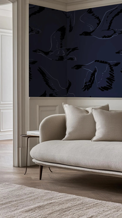 a living room with a white sofa and a dark blue wall with a repeating pattern of black birds.