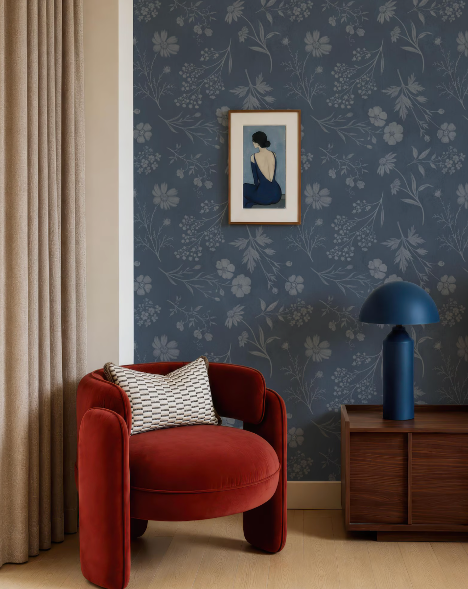 a cozy living room with a red armchair, a wooden side table with a blue lamp, and a framed artwork on the wall.