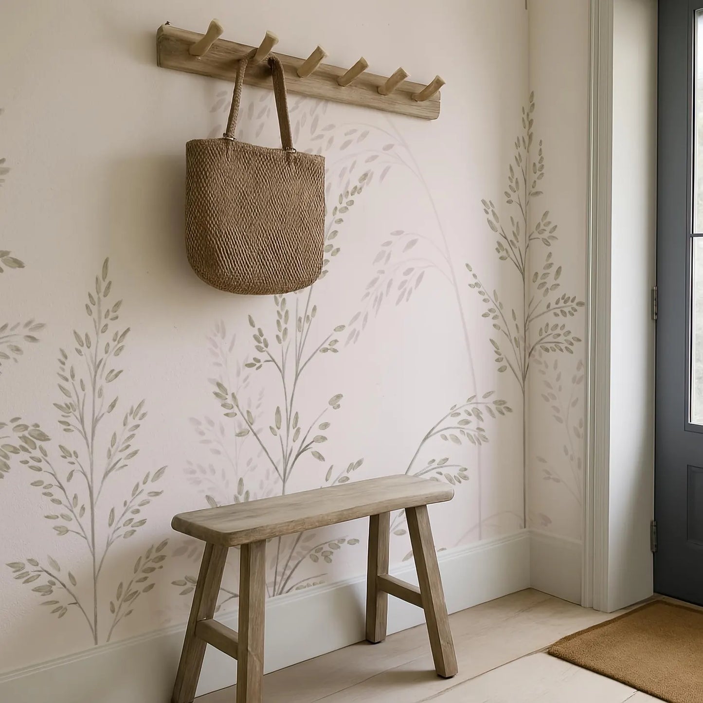 a wooden bench with a woven bag hanging on a wooden rack above it, set against a wall with a leaf-patterned wallpaper.