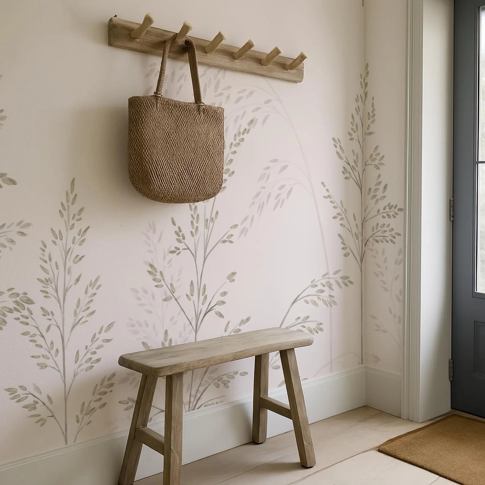 a wooden bench with a woven bag hanging on a wooden rack above it, set against a wall with a leaf-patterned wallpaper.