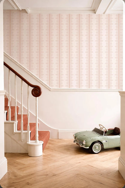 a vintage green toy car parked on a wooden floor next to a staircase with a white railing.