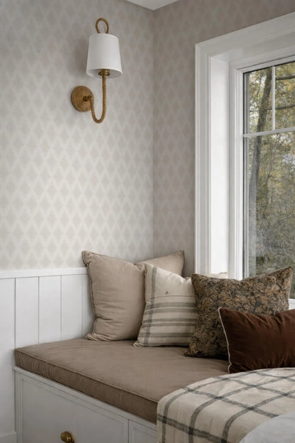 a cozy corner of a room with a white wall, a window, and a bed with a brown and white striped pillow.