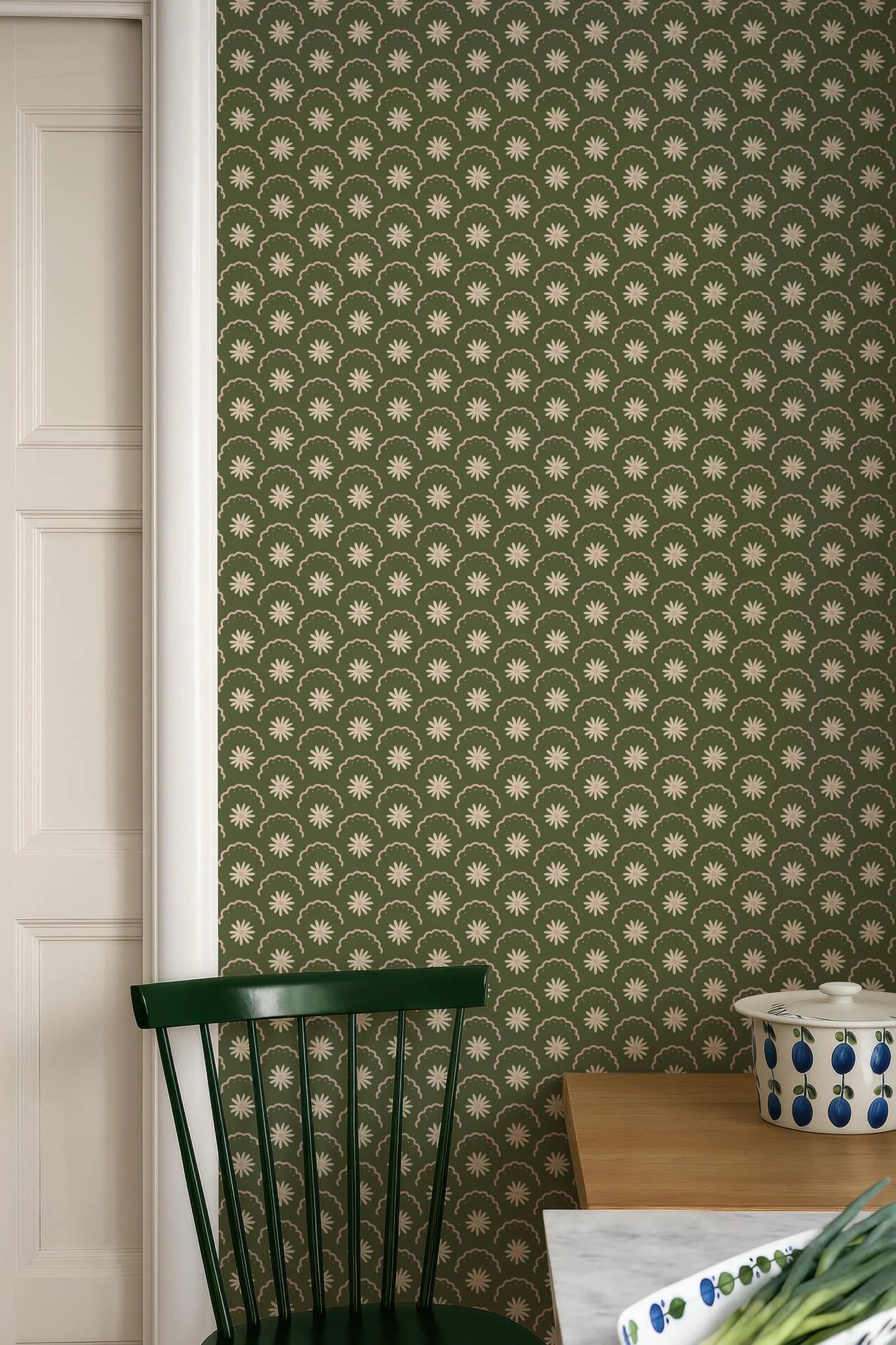 a green chair, a wooden table, and a patterned wallpaper with a repeating star design.