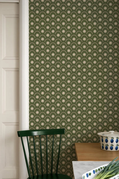 a green chair, a wooden table, and a patterned wallpaper with a repeating star design.