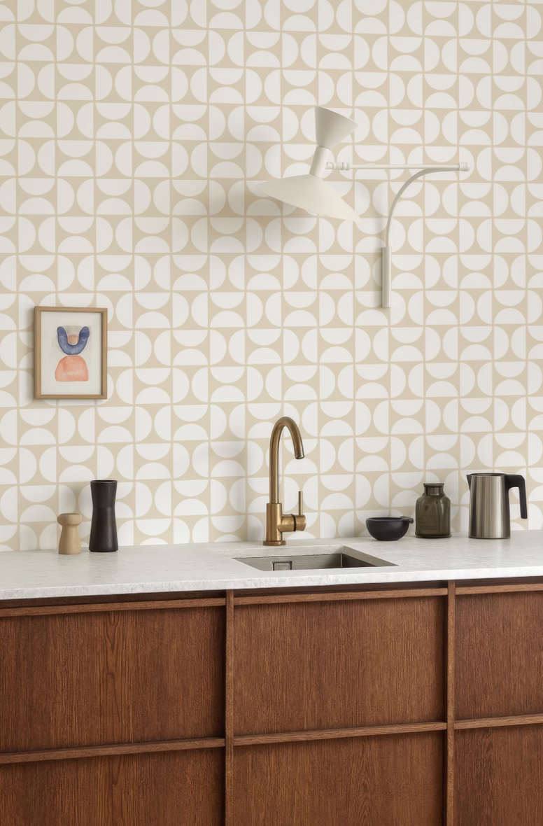 a modern kitchen with a white and beige geometric pattern on the walls, a wooden cabinet, a sink, and various kitchen accessories such as a coffee maker, a bowl, and a vase.
