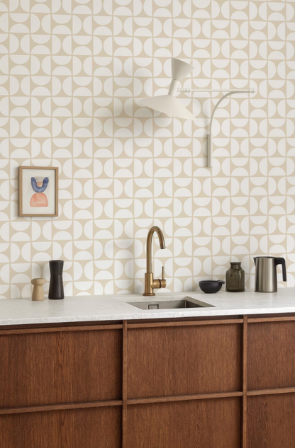 a modern kitchen with a white and beige geometric pattern on the walls, a wooden cabinet, a sink, and various kitchen accessories such as a coffee maker, a bowl, and a vase.