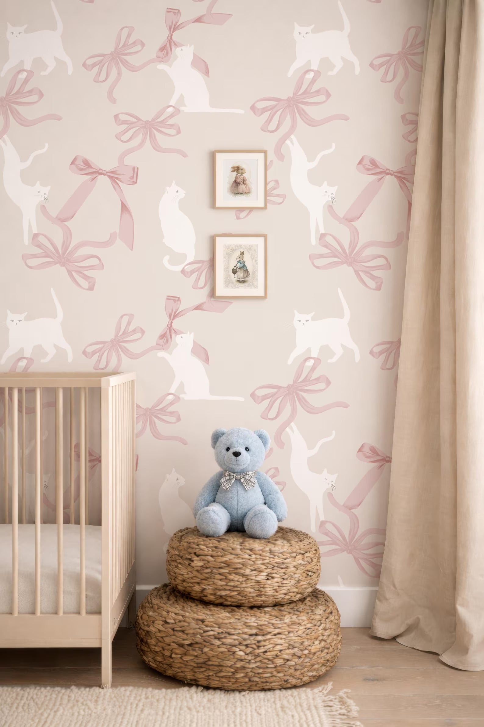 A baby's room with a wooden crib, a blue teddy bear, and a wall with a pink and white cat pattern wallpaper.