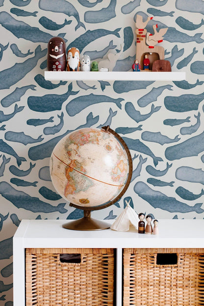 a wallpapered wall with a globe, wooden toys, and wicker storage bins below it.