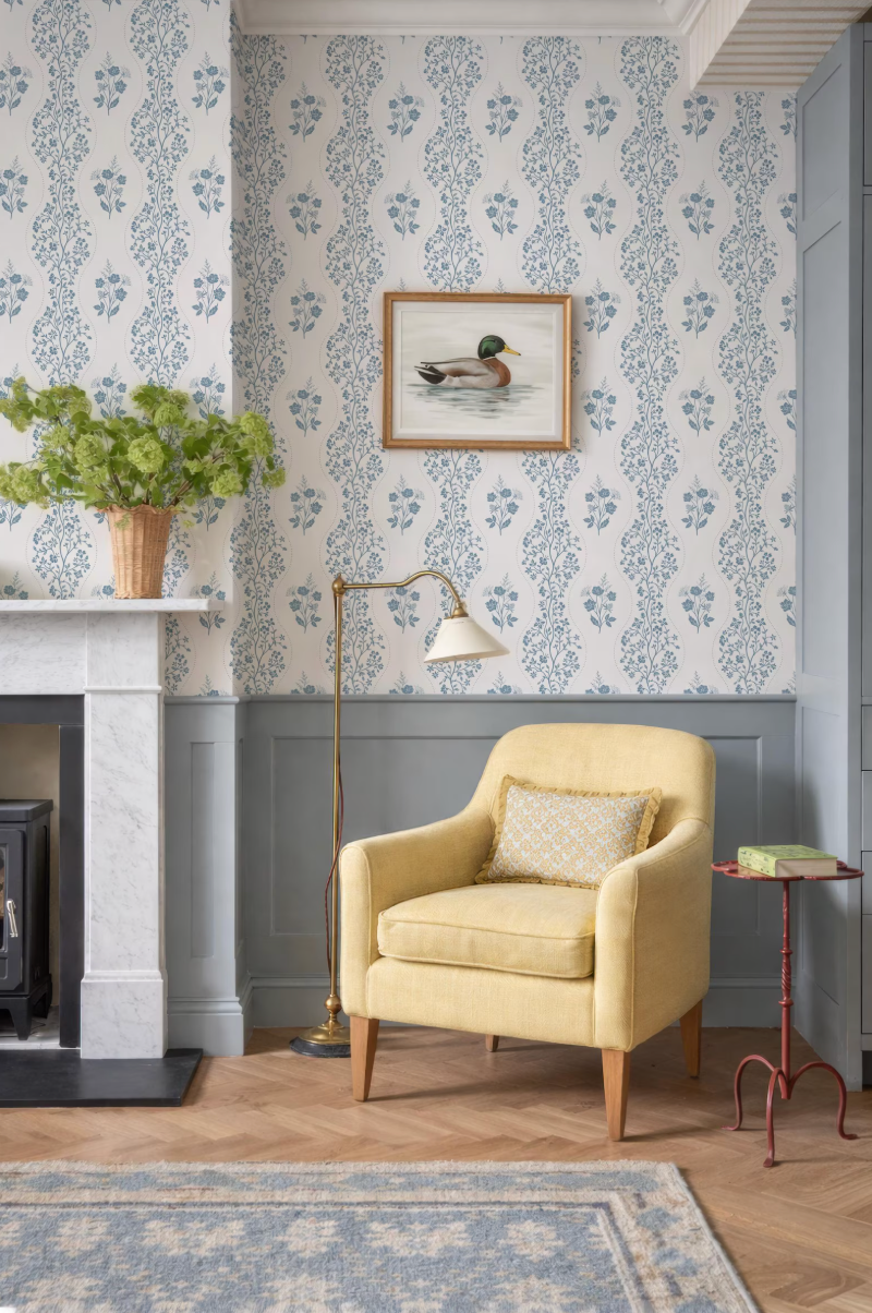 a cozy living room with a yellow armchair, a fireplace, a framed picture of a duck, and a floor lamp.