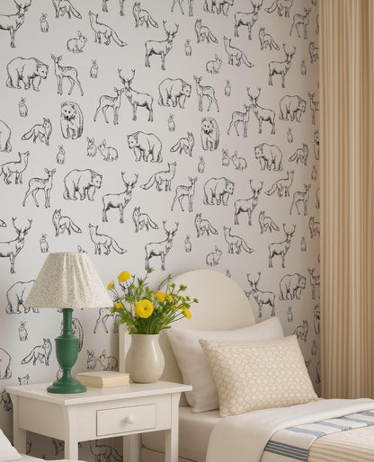 a bedroom with a white bed, a nightstand with a lamp and a vase of yellow flowers, and a wallpapered wall with a repeating pattern of black and white animal illustrations.