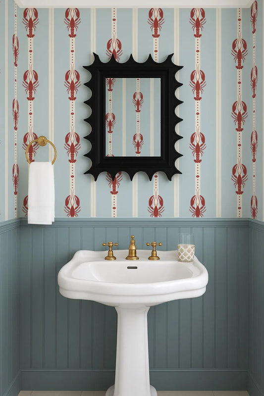 a bathroom with a white pedestal sink, a mirror with a black frame, and a lobster-themed wallpaper.