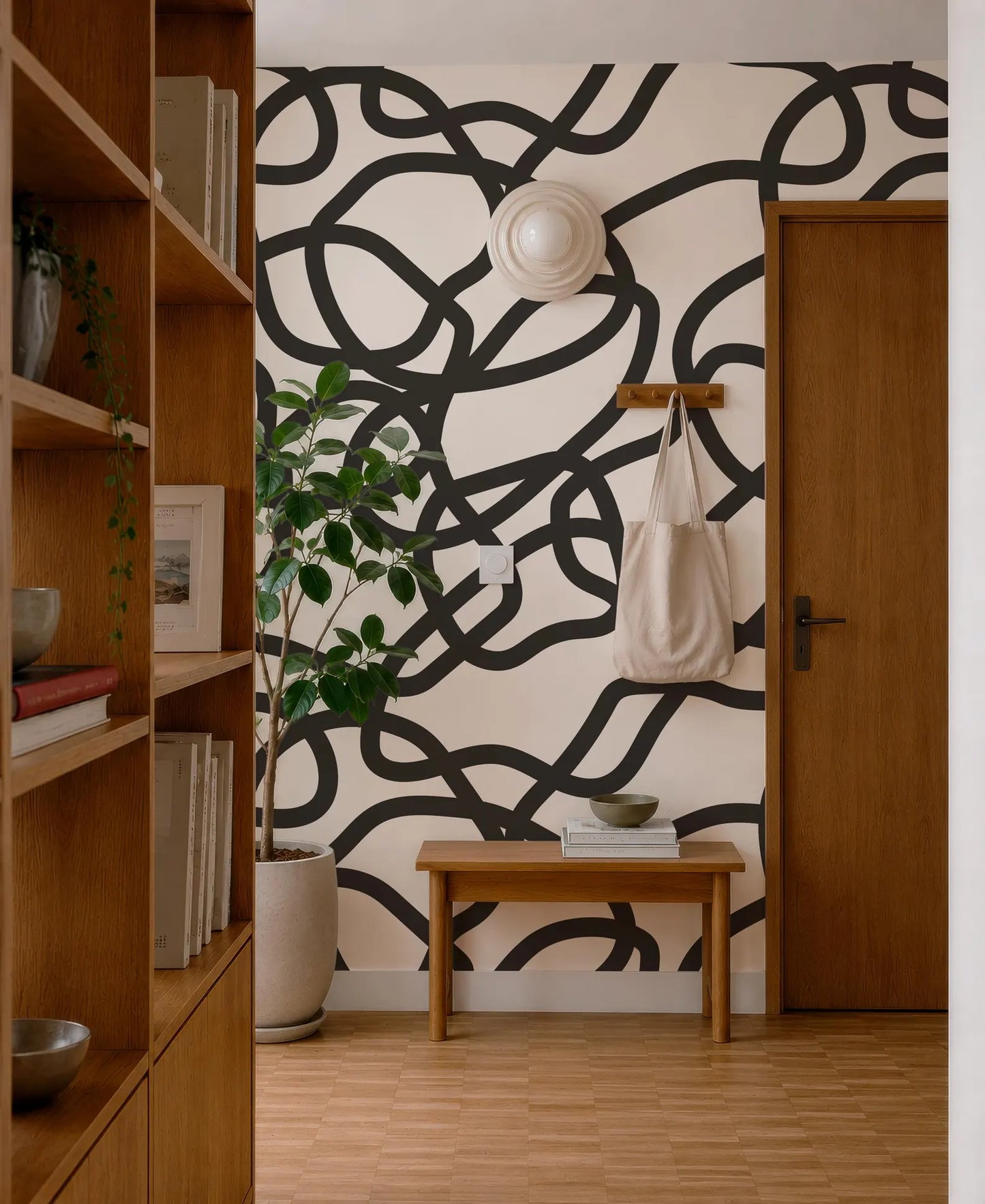 a modern and stylish interior design with a black and white abstract pattern on the wall behind a wooden bench. The room also includes a bookshelf, a potted plant, and a wooden door.