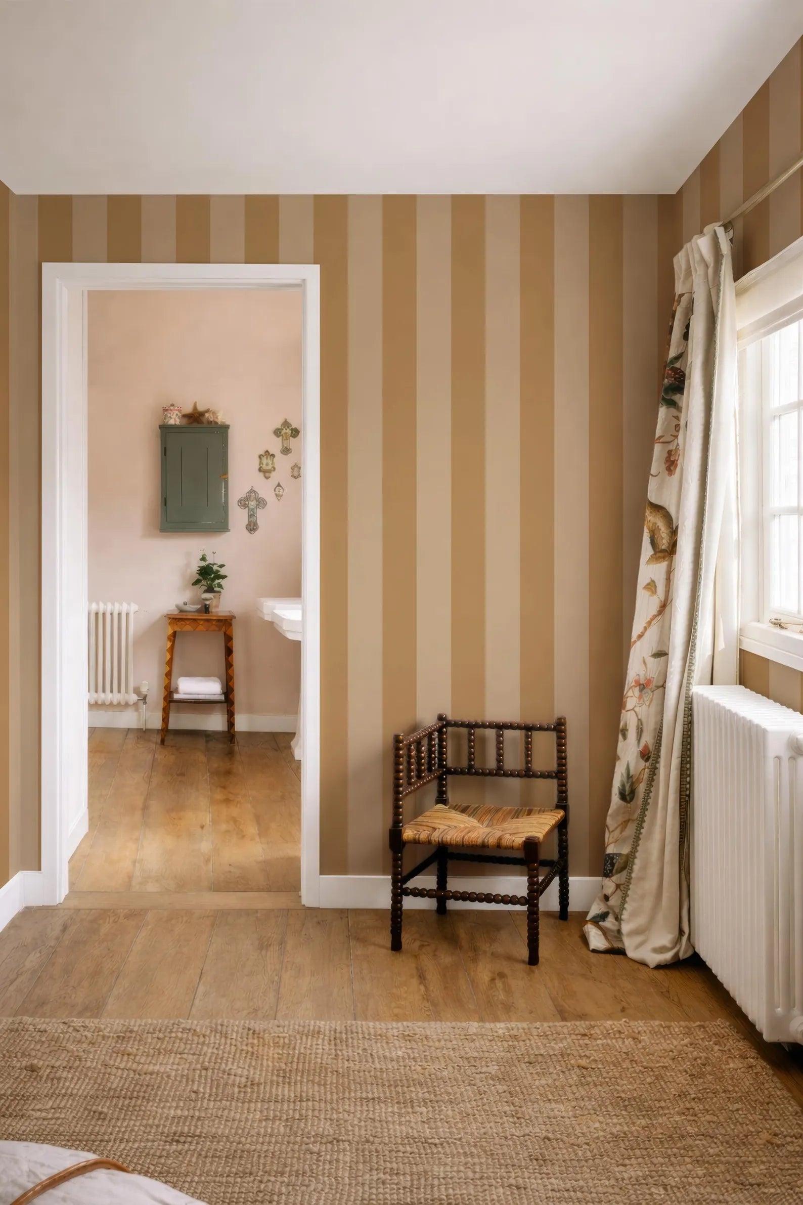 a cozy and inviting room with a wooden chair, a striped wall, and a window with a curtain. The room appears to be a living space with a rug on the floor and a small table with a plant.