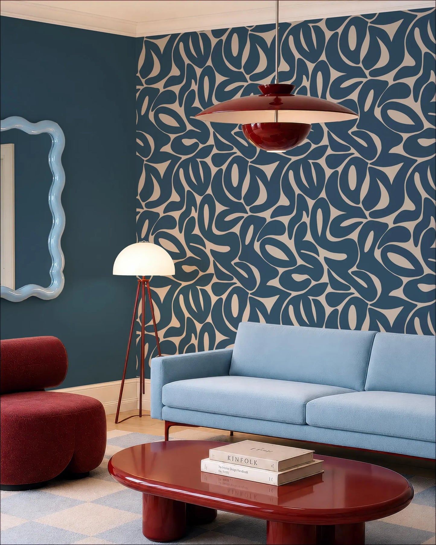 a modern living room with a blue sofa, a red armchair, and a red coffee table. The room has a patterned blue and white wall, and a red pendant light hangs above the sofa. There is also a white floor lamp in the corner of the room.