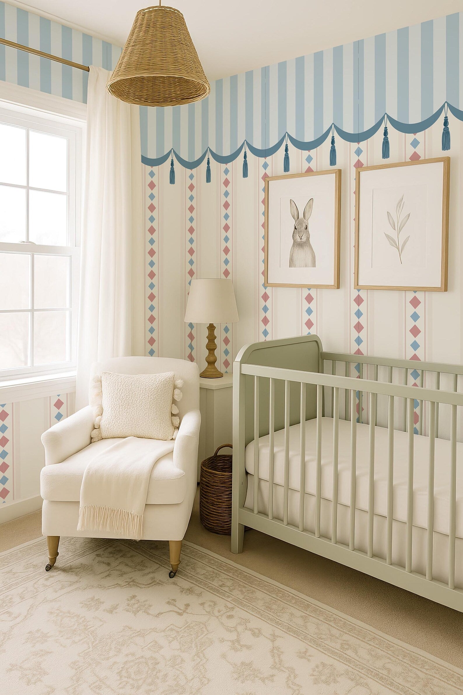 a cozy nursery room with a white crib, a white armchair, and a lamp. The room has a striped wallpaper and a wicker pendant light hanging from the ceiling. There is a window in the room, and the walls are decorated with two framed pictures of rabbits.