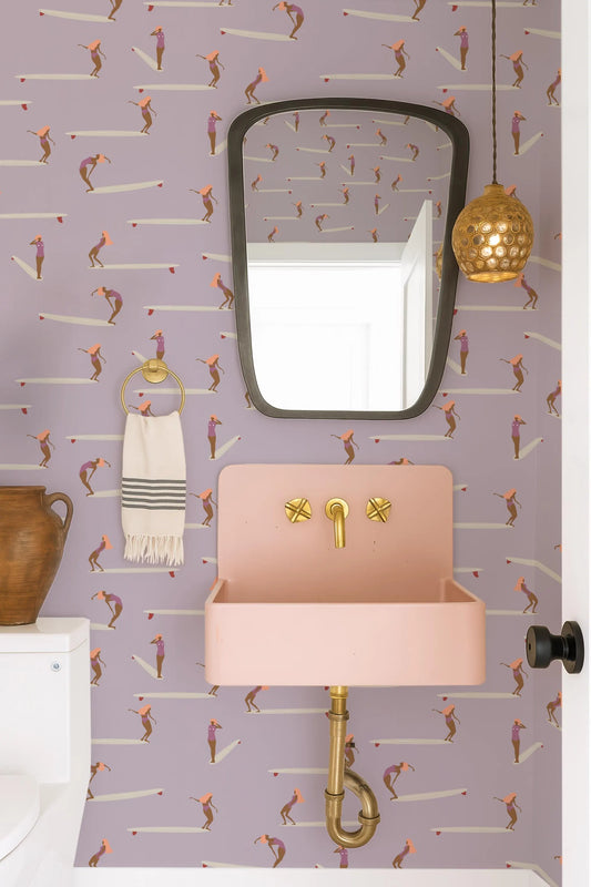 a bathroom with a pink sink, a mirror, and a towel rack. The walls are decorated with a pattern of cartoon-like figures, and there is a pendant light hanging above the sink.