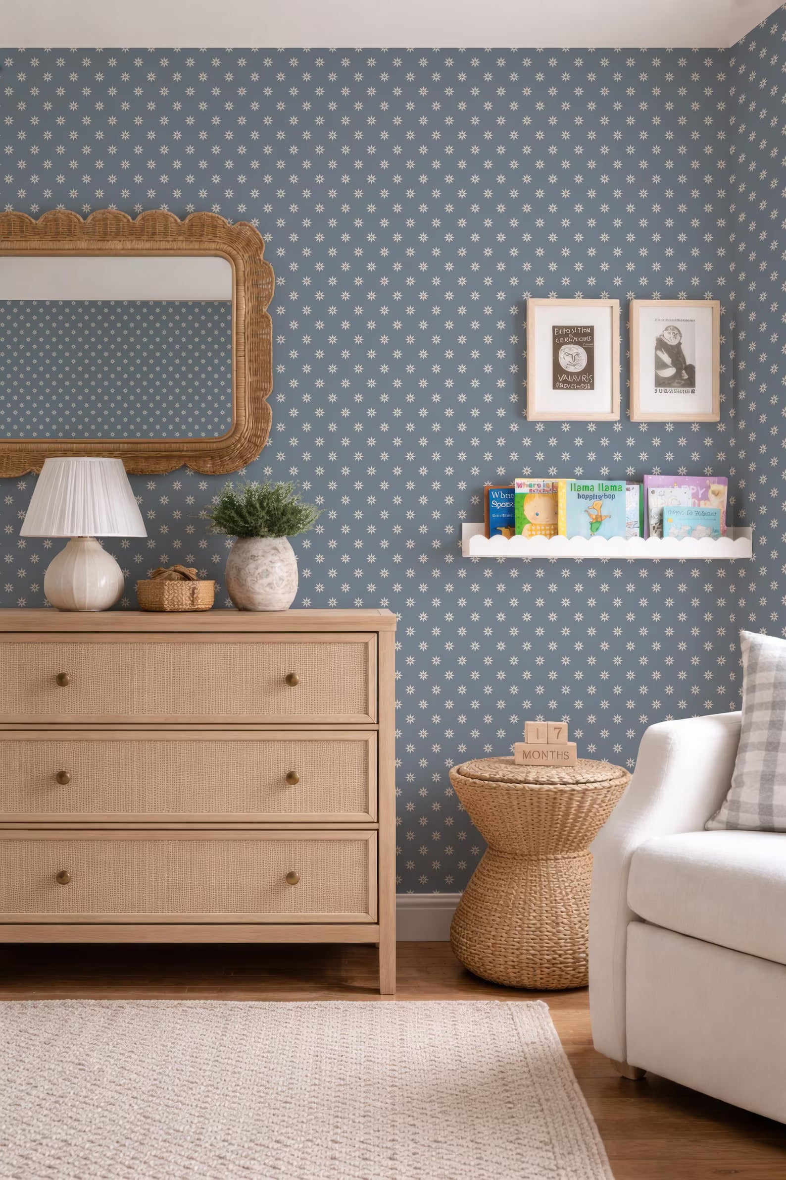 a cozy and well-decorated living room with a blue and white polka dot wallpaper, a wooden dresser, a wicker side table, a white sofa, and a mirror.