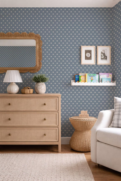 a cozy and well-decorated living room with a blue and white polka dot wallpaper, a wooden dresser, a wicker side table, a white sofa, and a mirror.