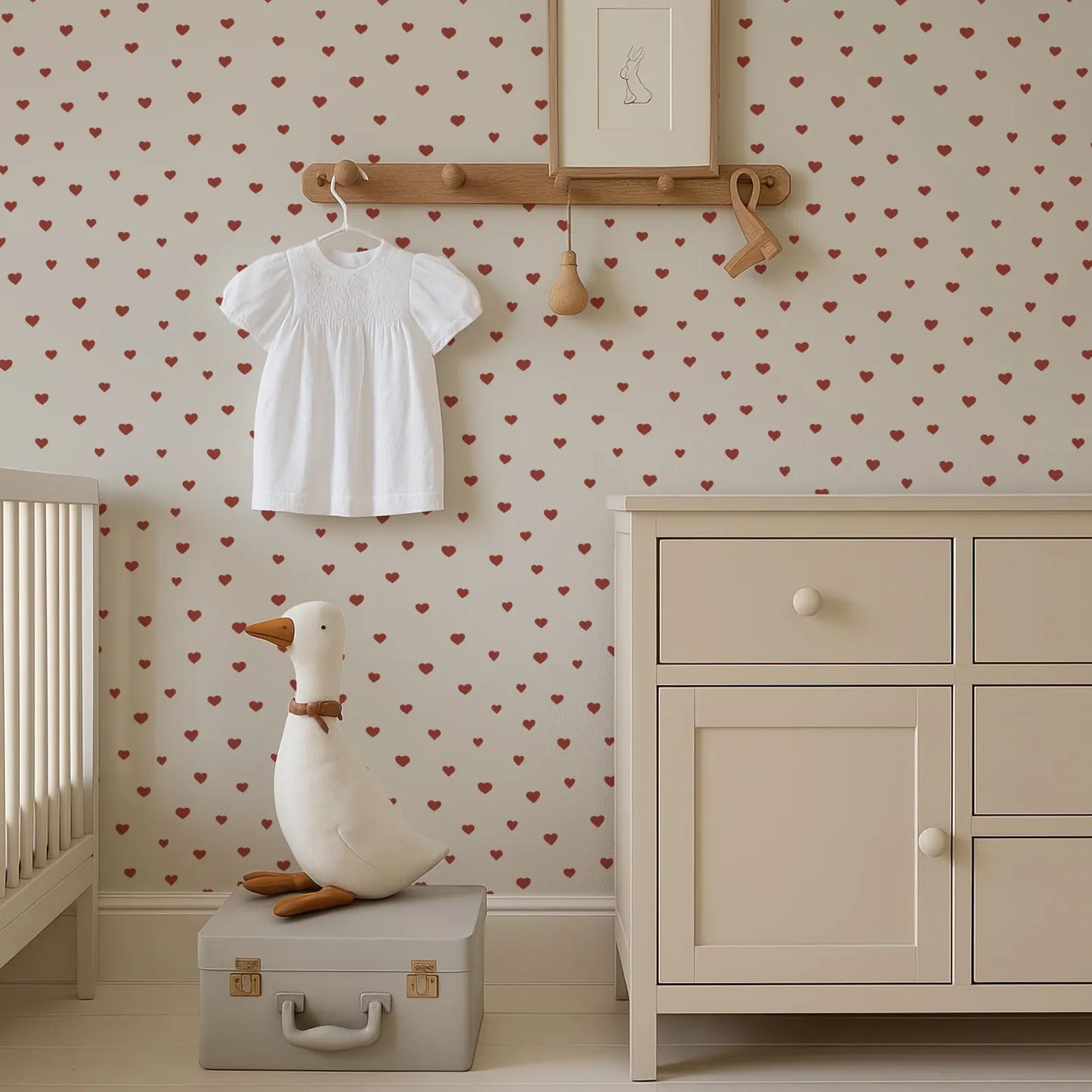 a nursery room with a white dresser, a stuffed duck toy, and a framed picture on the wall.