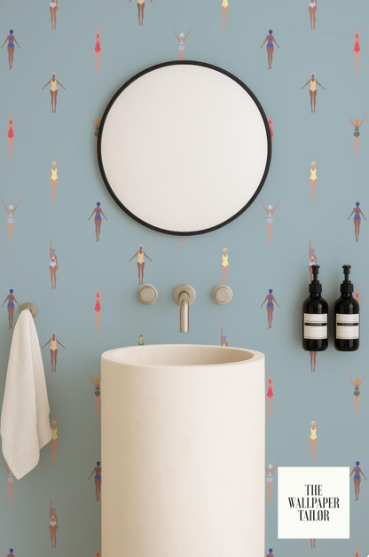 a bathroom with a white sink, a round mirror, and a towel rack. The wall behind the sink has a pattern of colorful swimming figures.