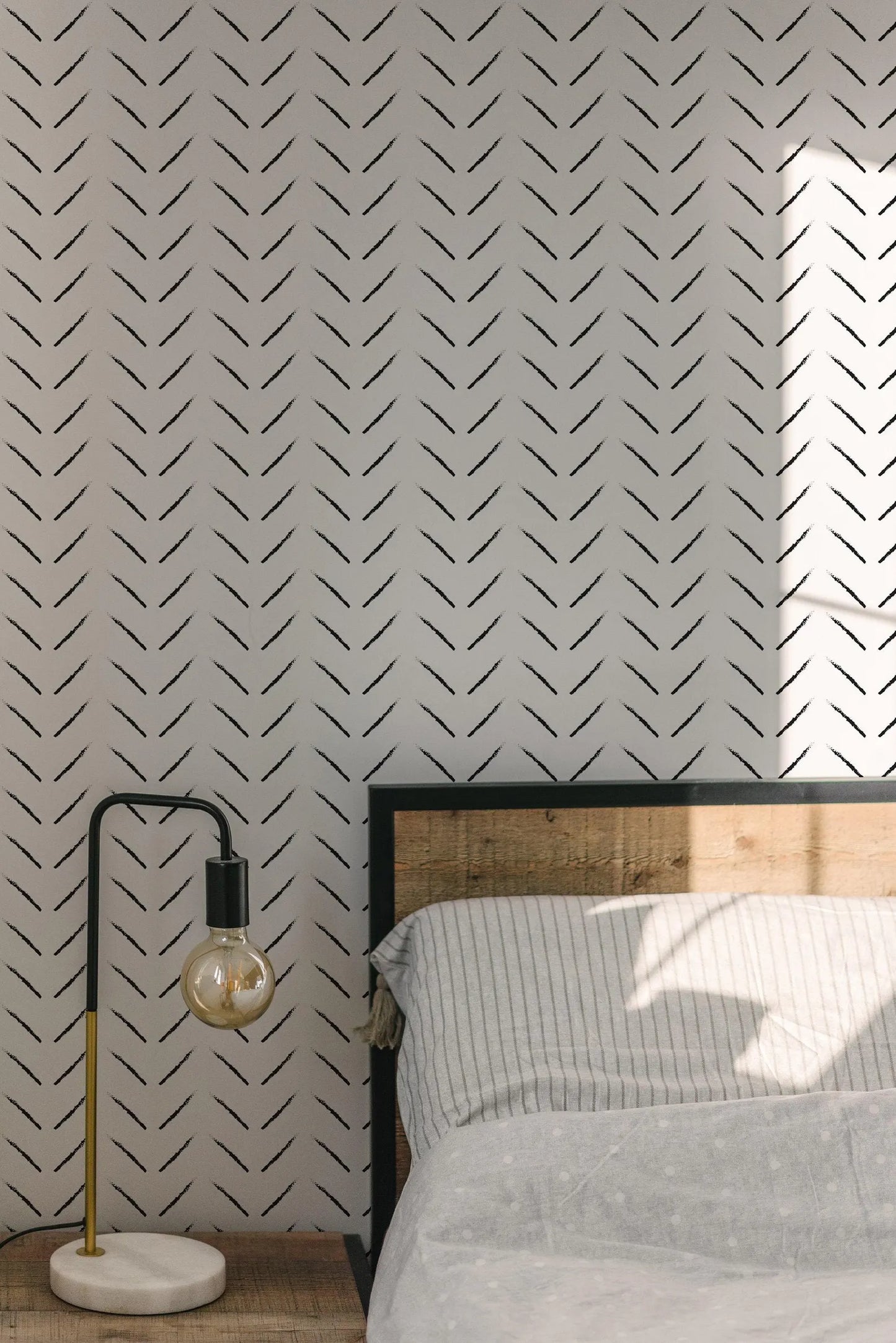 a bedroom setting with a bed, a lamp, and a patterned wallpaper.