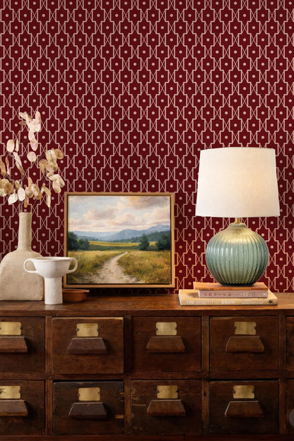 a wooden dresser with a painting, a lamp, and a vase on top. The dresser has multiple drawers and a mirror. The wall behind the dresser has a red and white patterned wallpaper.