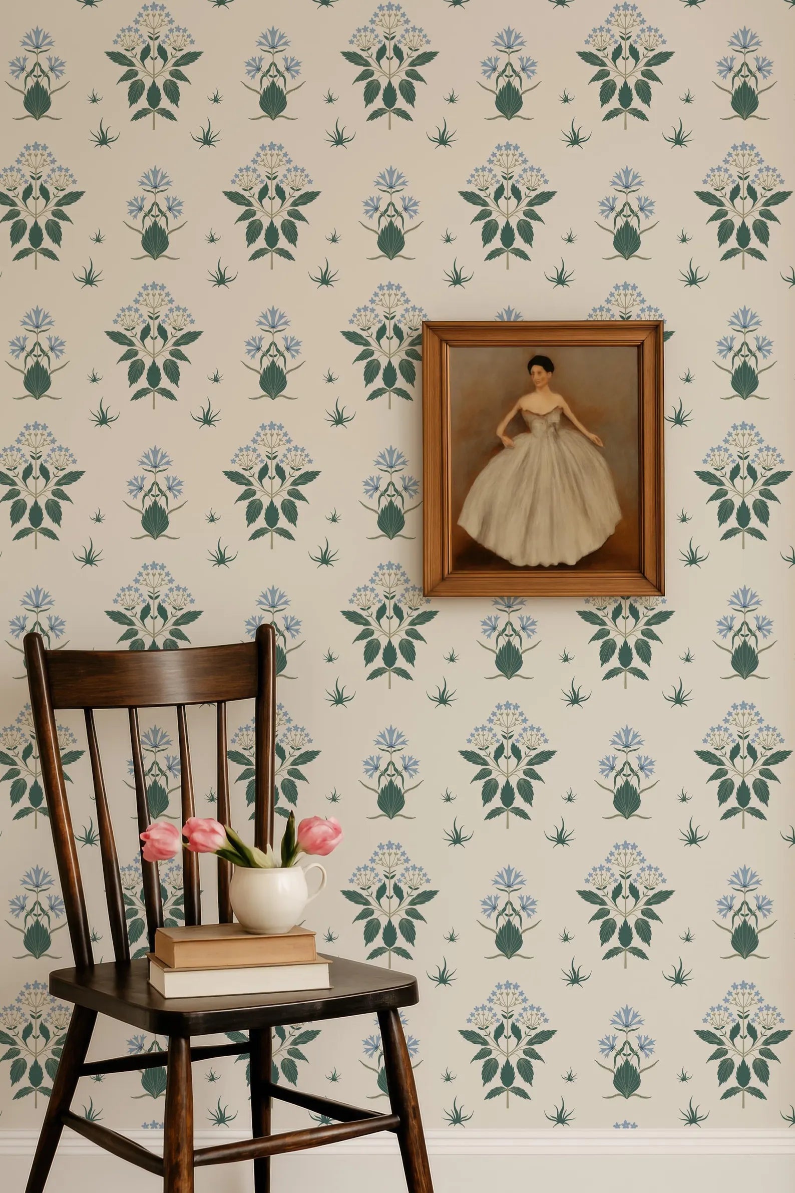 a wooden chair with pink flowers in a white vase, a framed painting of a woman in a white dress, and a bookshelf with books. The background has a floral wallpaper pattern.
