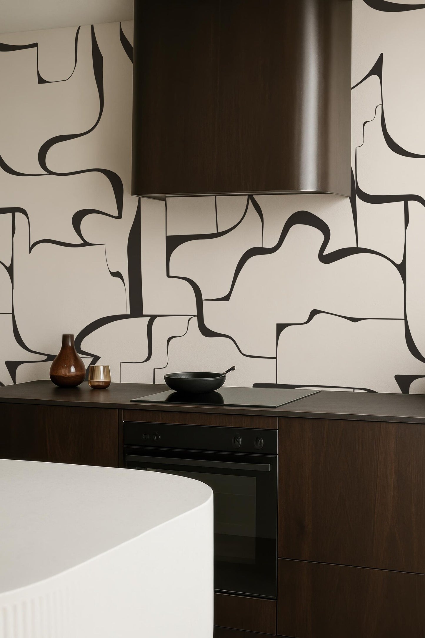 a modern kitchen with a sleek black stove and a white countertop. The kitchen has a minimalist design with a black and white abstract pattern on the walls.