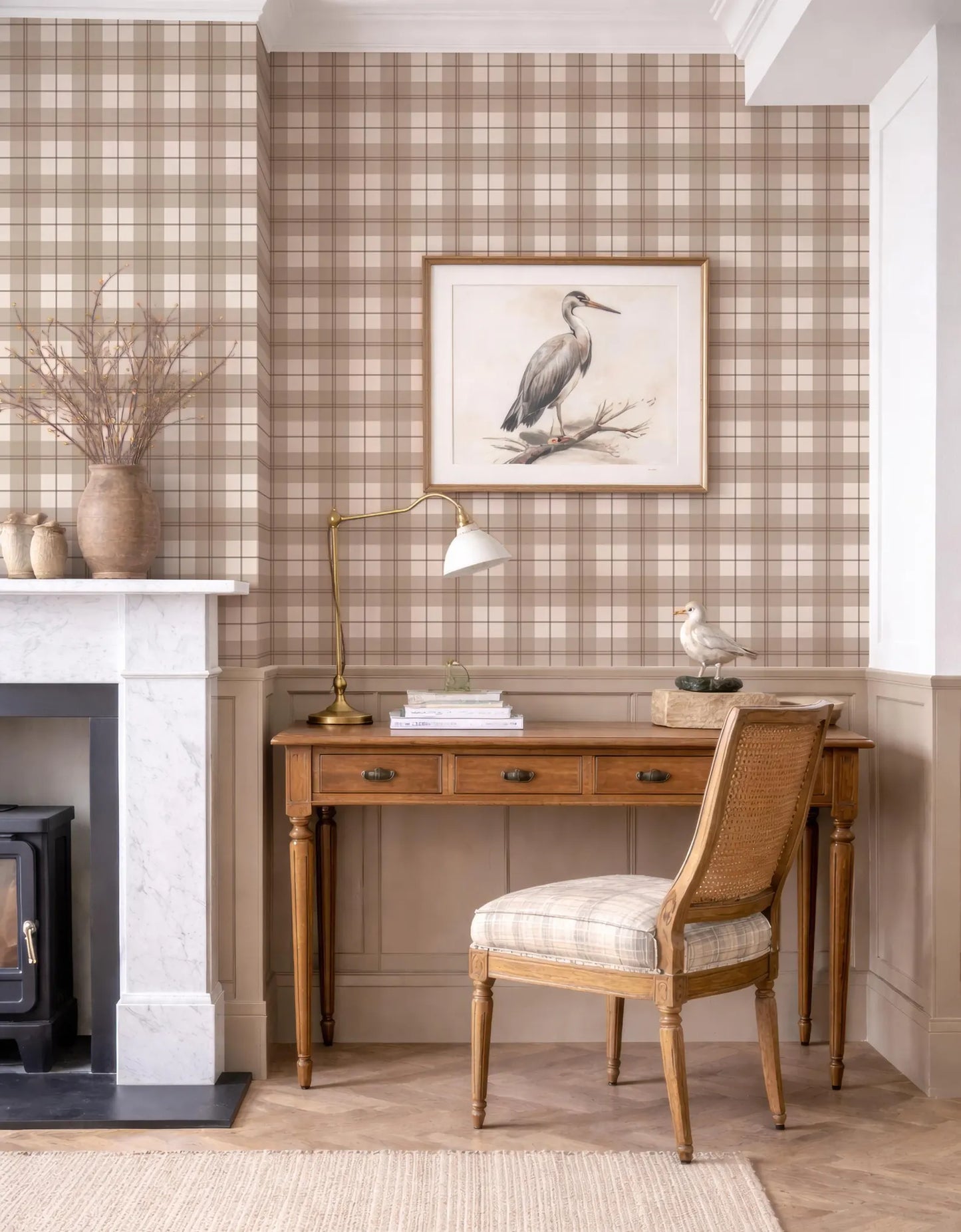 a cozy and well-decorated living room with a wooden desk, a lamp, a framed picture of a bird, and a fireplace.
