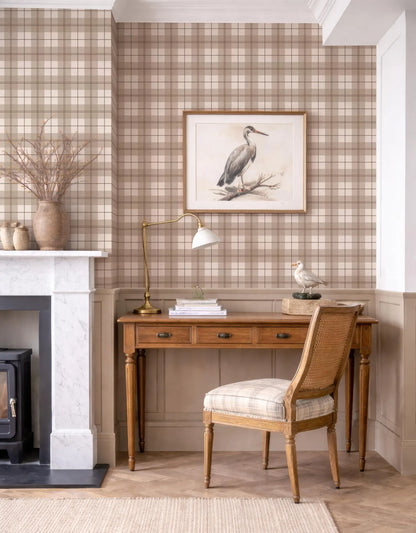 a cozy and well-decorated living room with a wooden desk, a lamp, a framed picture of a bird, and a fireplace.
