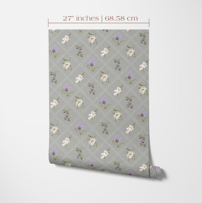 a gray wall with a repeating pattern of white and purple flowers and leaves. The pattern is displayed on a roll of wallpaper or paper, which is being measured for size.