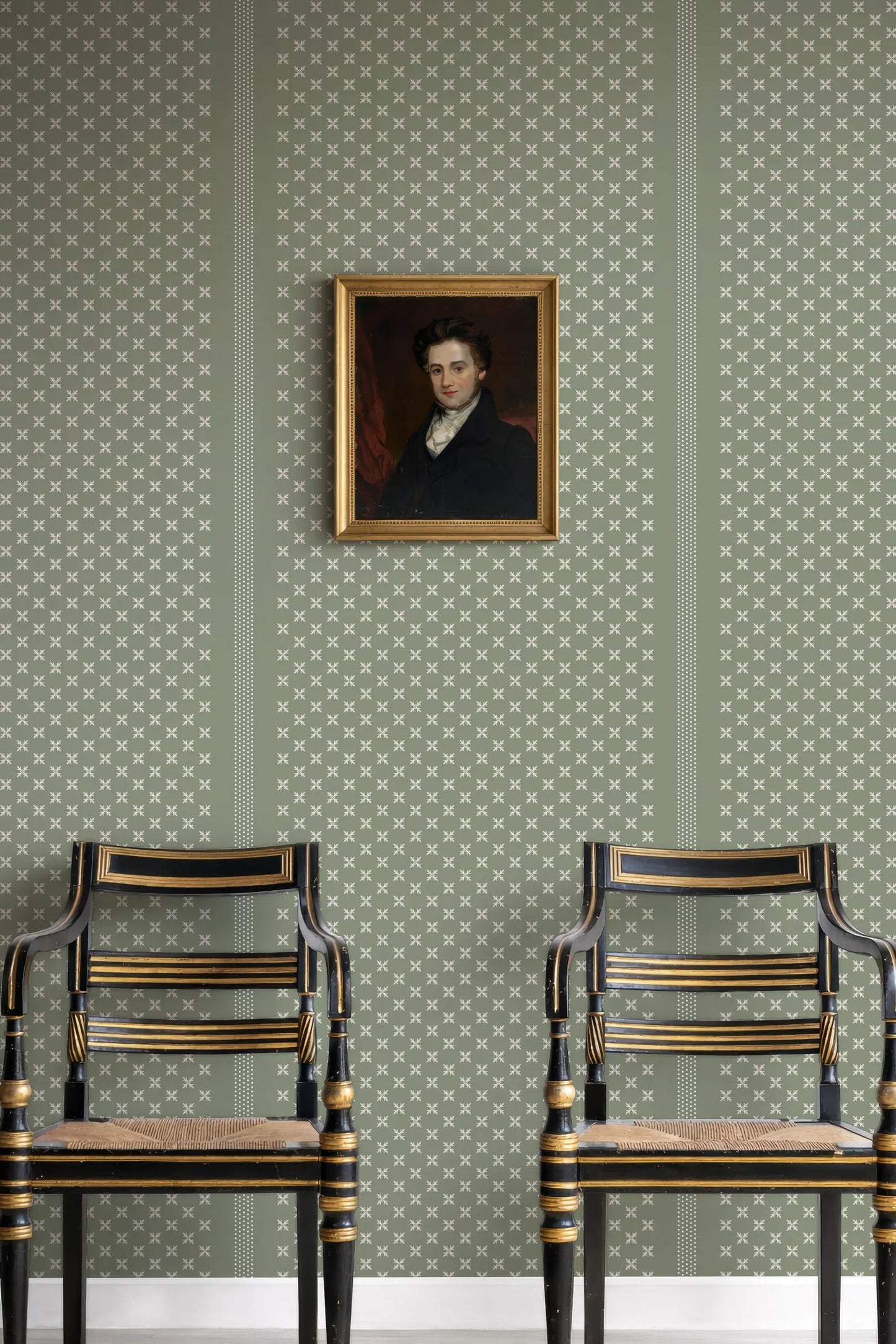 a portrait of a man hanging on a wall, with two black chairs positioned in front of it.