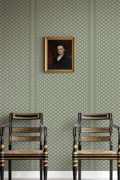 a portrait of a man hanging on a wall, with two black chairs positioned in front of it.