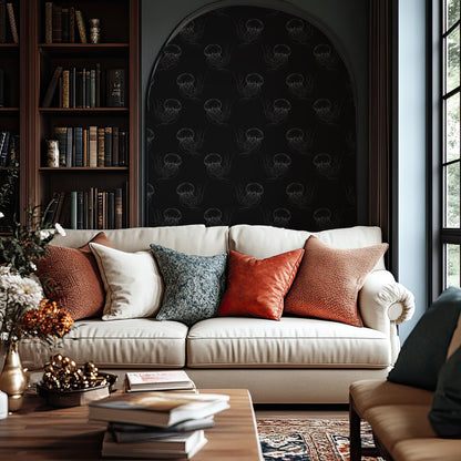 a cozy living room with a white sofa adorned with colorful throw pillows, a wooden coffee table, and a bookshelf filled with books. The room has a dark, moody atmosphere with a black and white patterned wallpaper, and a large arched window that allows natural light to enter the space.