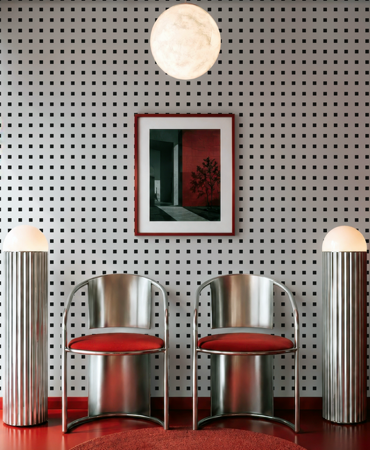 a modern interior design with a black and white checkered pattern on the walls, two chrome chairs with red cushions, and a framed artwork above the chairs.