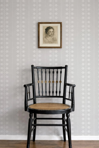 a black wooden chair with a woven seat, positioned against a gray wall with a framed portrait hanging above it.